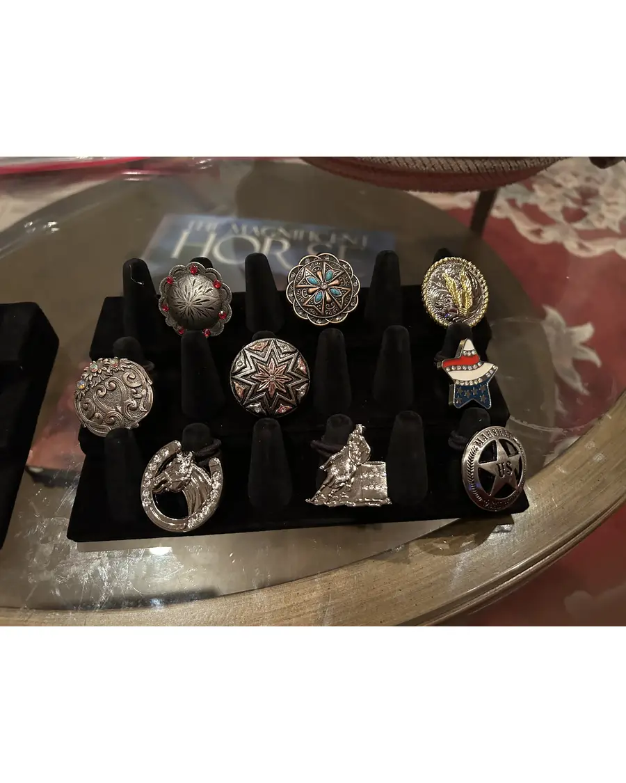 Display of handcrafted concho rings featuring western motifs including horses, stars, barrel racer, and US Marshal badge