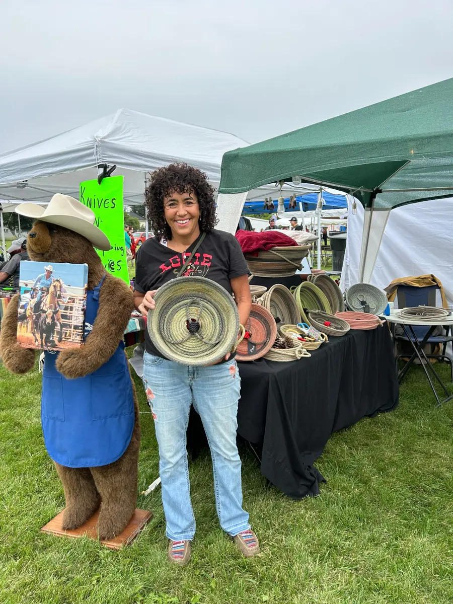 Sheryl smiling at a show booth holding a handcrafted rope basket