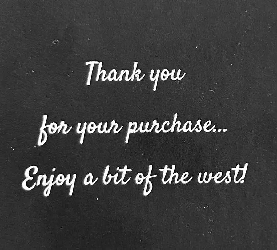 Hand-lettered script reading 'Thank you for your purchase... Enjoy a bit of the west!' on dark fabric