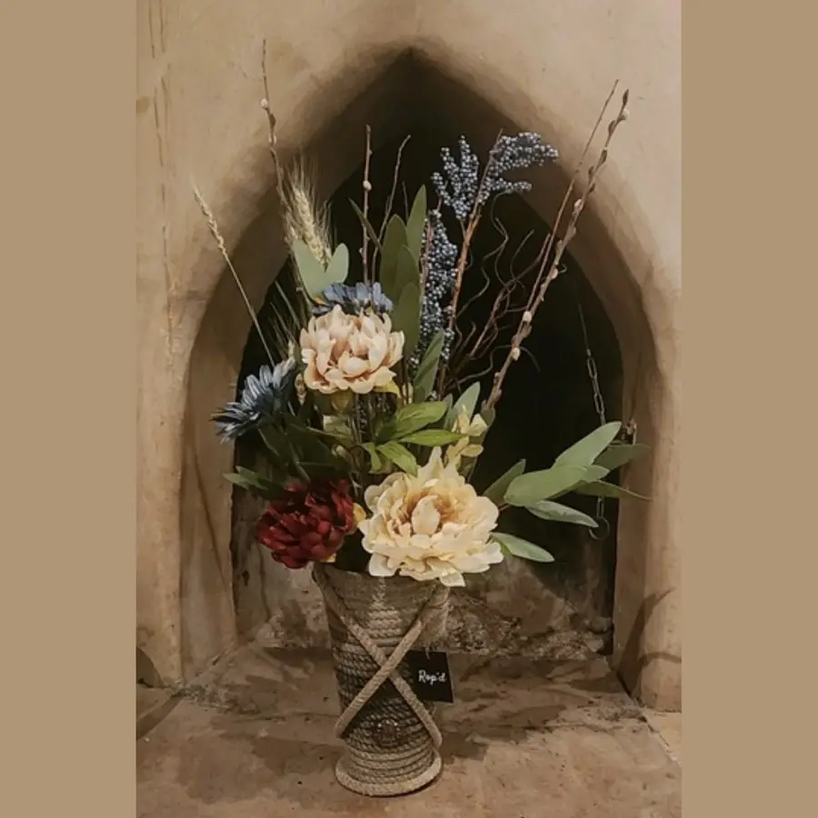 Handcrafted rope vase with a floral arrangement set inside a stone arch alcove