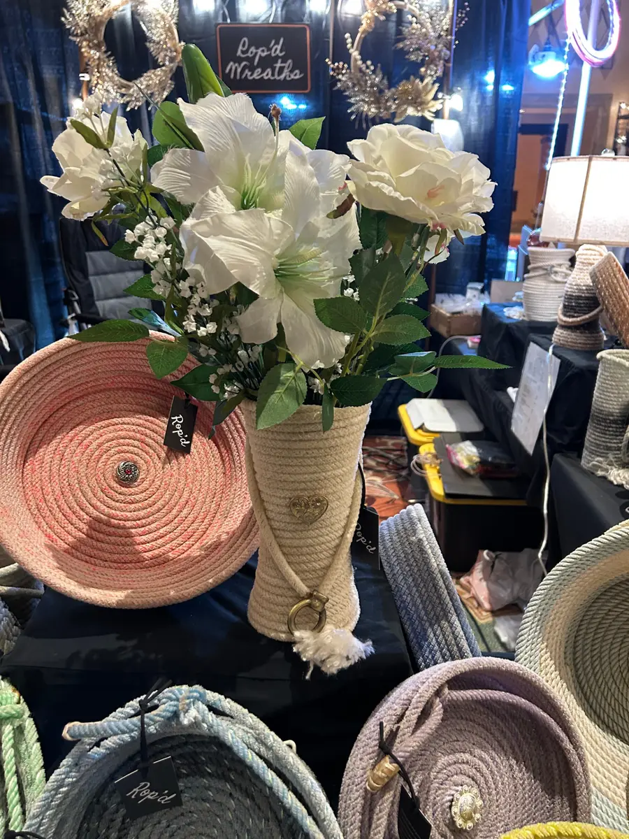 Rop'd Wreaths booth display with a rope vase of white flowers and pastel rope baskets